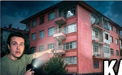 Pembe apartman ve elinde fener tutan genç adam